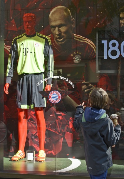 Một cậu bé người Đức thích thú đứng trước cửa hàng lưu niệm có hình Robben và áo đấu của thủ môn Neuer ở Munich.